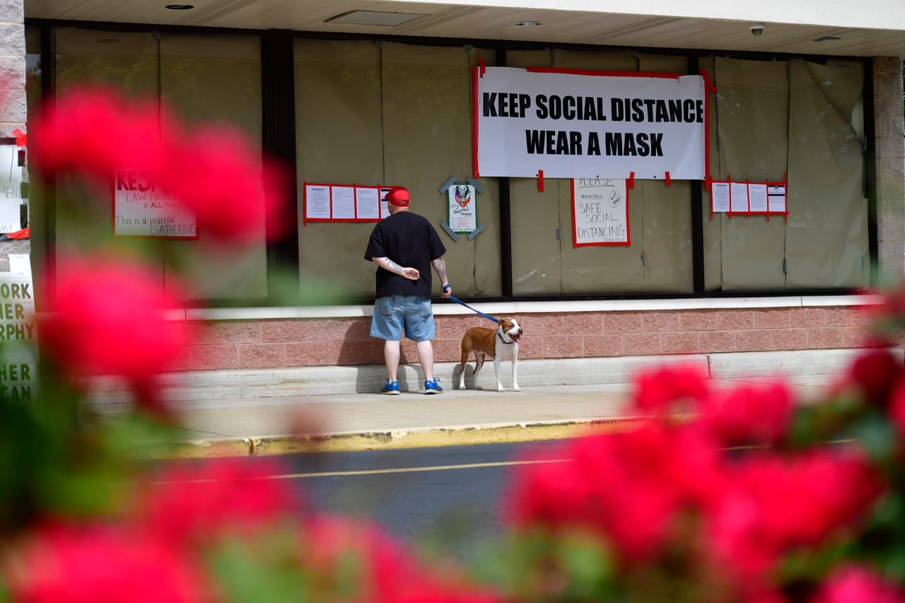 Un hombre que paseaba a su perro el miércoles lee las pancartas y los avisos fuera de gimnasio Atilis. Una de las pancartas tiene un mensaje que dice "mantega la distancia social usando una mascarilla".
<br>Nueva Jersey está en la primera fase del plan de apertura. Los primeros negocios autorizados para abrir son construcción, venta minorista, playas, cines al aire libre desde el auto y servicios religiosos que deben operar con limitaciones.