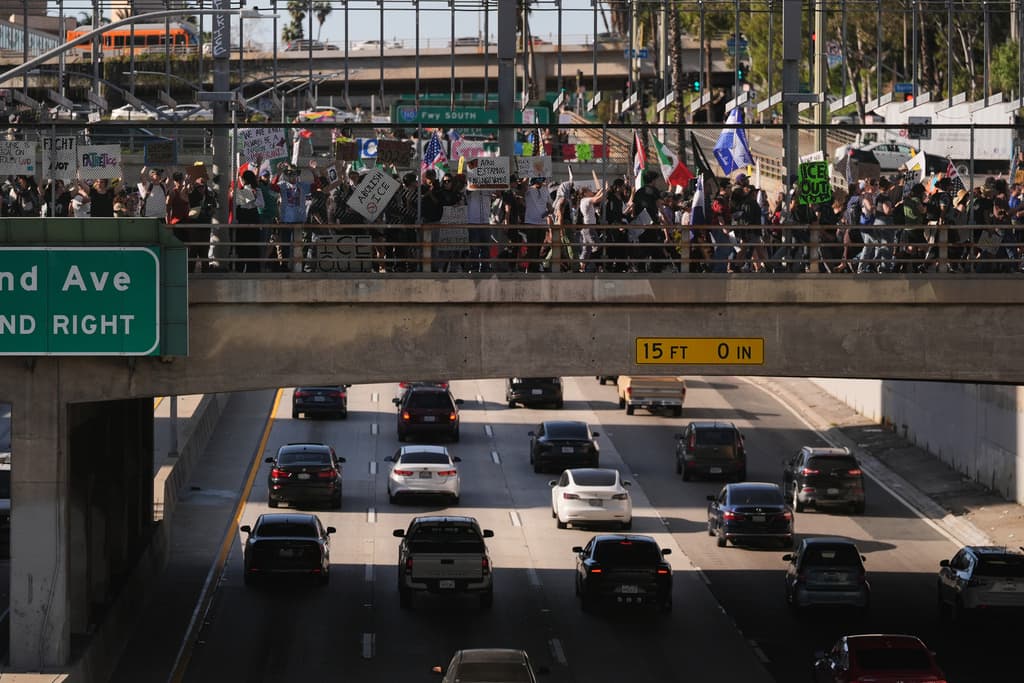 Personas cruzan un puente sobre una autopista del centro durante una protesta en Los Ángeles.