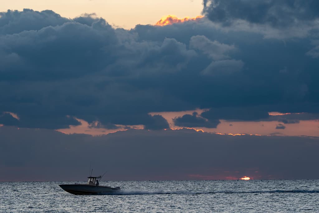 Un bote pasa durante el amanecerde Navidad en la playa de Palm Beach, en el sur de la Florida.