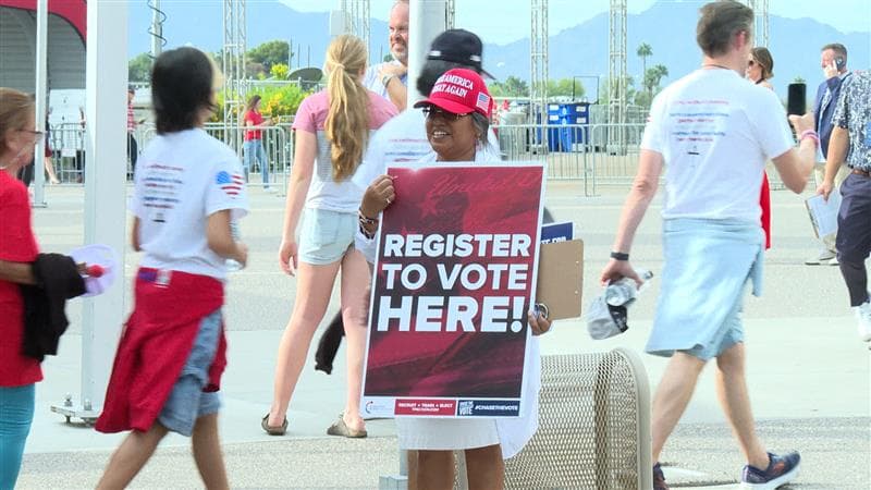 Afuera, personas invitando a los asistentes y a quienes se encontraban en la zona, a
<b>registrarse para votar</b>.