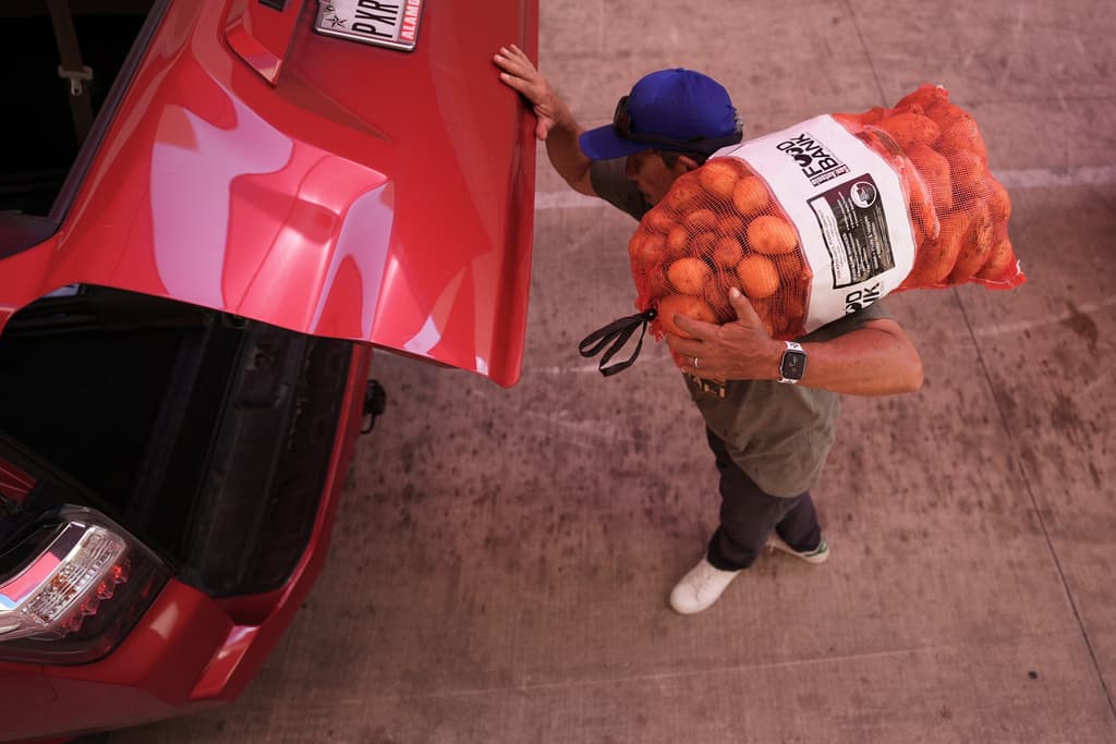 El voluntario Joel Hernandez ayuda a cargar un vehículo durante una distribución de alimentos dirigida a hogares de empleados federales afectados por el cierre, así como a beneficiarios de SNAP, en San Antonio, el 27 de octubre de 2025.