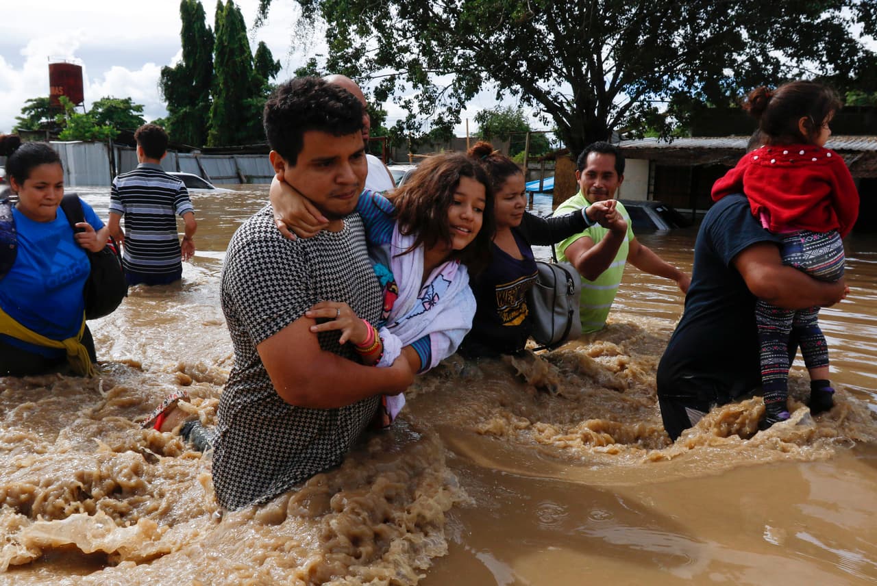 Además, se registran al menos otras 8 víctimas en Honduras. En la imagen, residentes de Jerusalén, Honduras, buscan ponerse a salvo en medio de las inundaciones. En ese país las lluvias afectaron sobre todo la zona norte y provocaron el desbordamiento de muchos de sus ríos, lo cual ocasionó serias inundaciones.