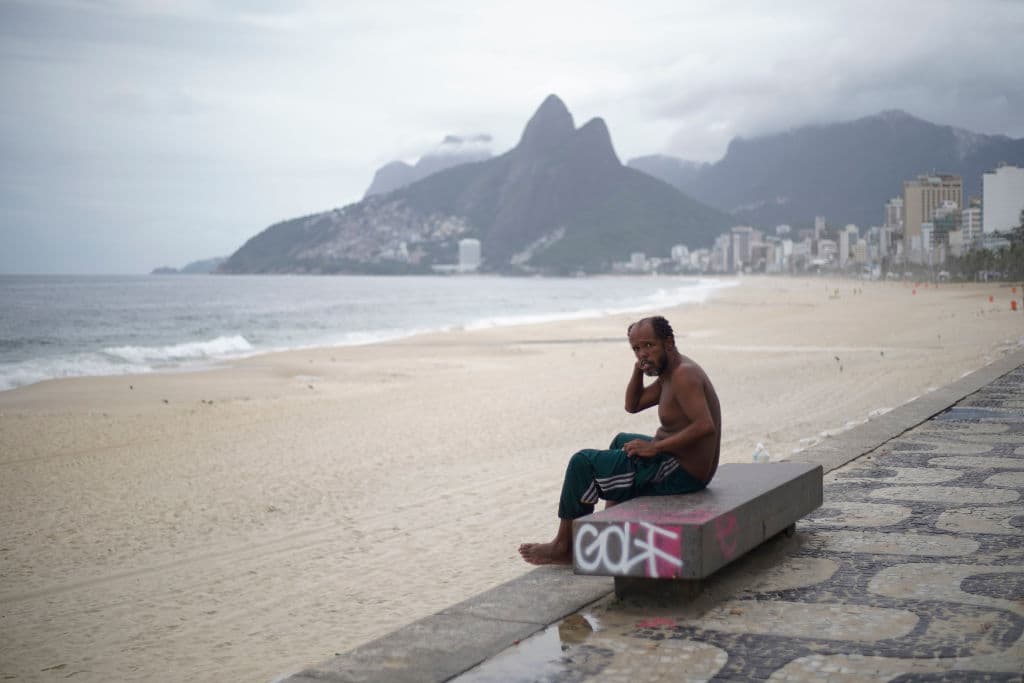 Un hombre sin hogar en la playa de Ipanema en Río de Janeiro, Brasil. El 21 de marzo, el gobierno del estado de Río de Janeiro impuso restricciones al transporte público. En América Latina se multiplican las medidas drásticas.
<br>