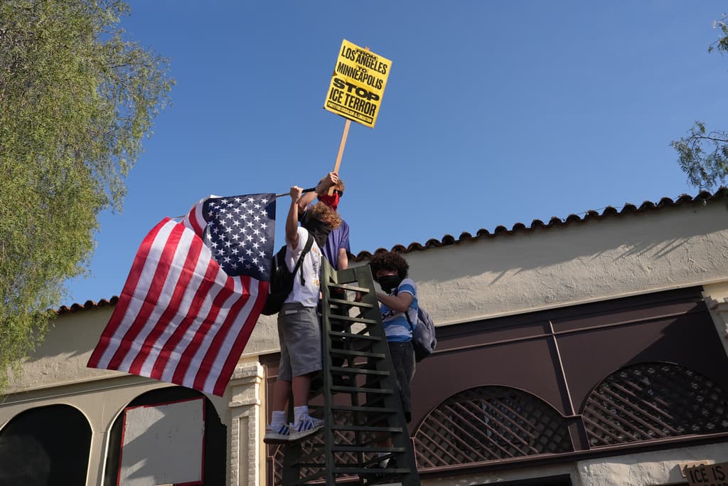 Personas ondeando banderas y sosteniendo carteles se unen a los manifestantes durante una protesta en Los Ángeles.