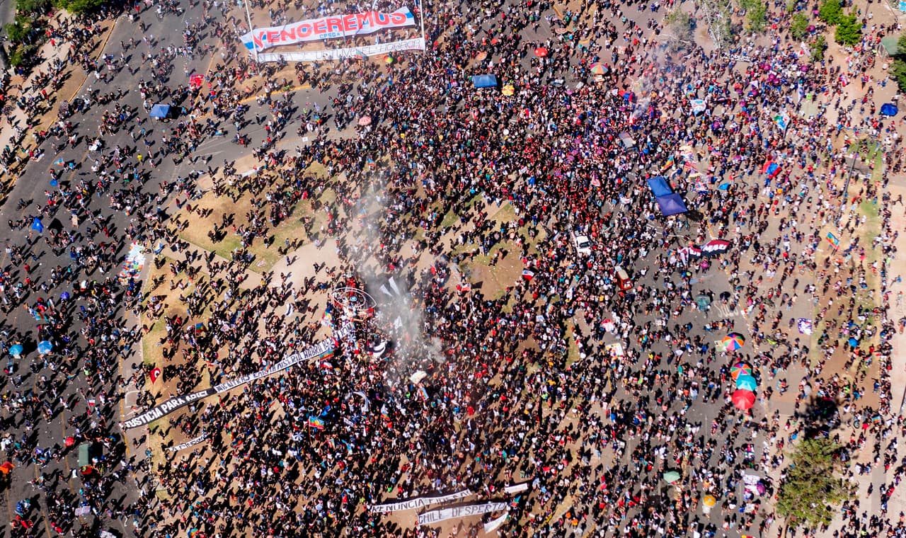 Los grupos de manifestantes comenzaron a llegar desde temprano hasta convertirse en decenas de miles las personas que se reunieron en este lugar, convertido en el epicentro de las protestas que estallaron el 18 de octubre de 2019.
<br>
<br>En su mayoría jóvenes pero también familias y personas mayores llegaron hasta esta plaza, rebautizada por los manifestantes como "Plaza de la Dignidad", para conmemorar el día en que "Chile despertó" pero también para volver a reencontrase en un masiva protestas tras meses en que la pandemia impuso una pausa en las manifestaciones chilenas.