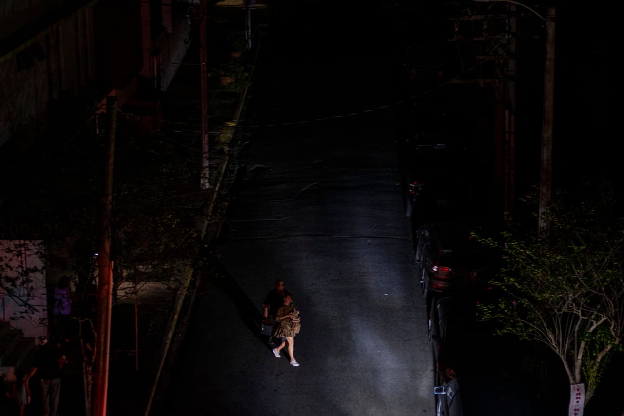 Una mujer cruza una calle oscura en San Juan en medio de los apagones que se generalizaron tras un incendio en la subestación de Monacillo.