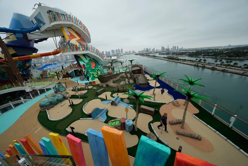 La gente prueba un campo de minigolf situado junto a toboganes de agua, encima de una cubierta en Icon of the Seas.