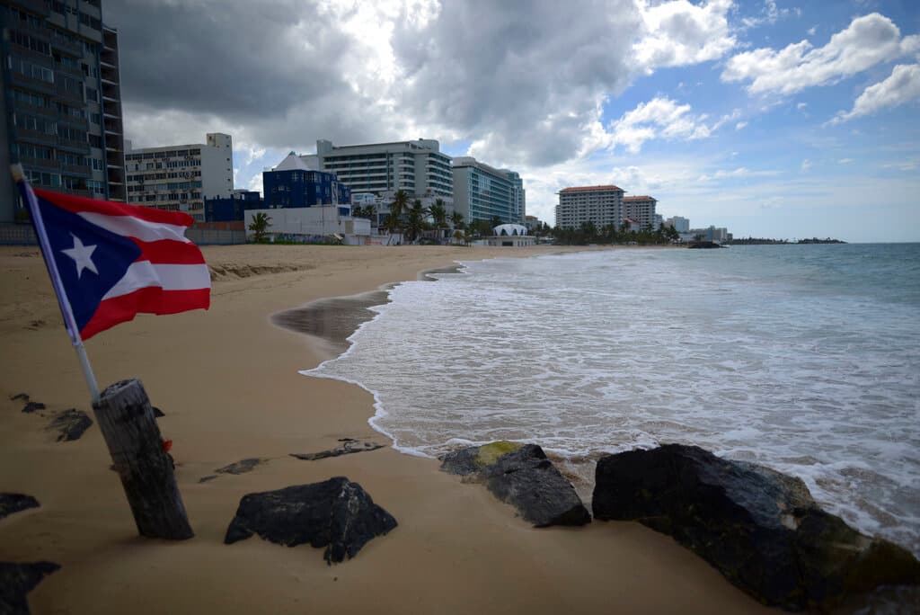 En esta fotografía de archivo del 21 de mayo de 2020, una bandera puertorriqueña ondea en una playa vacía en Ocean Park, en San Juan, Puerto Rico