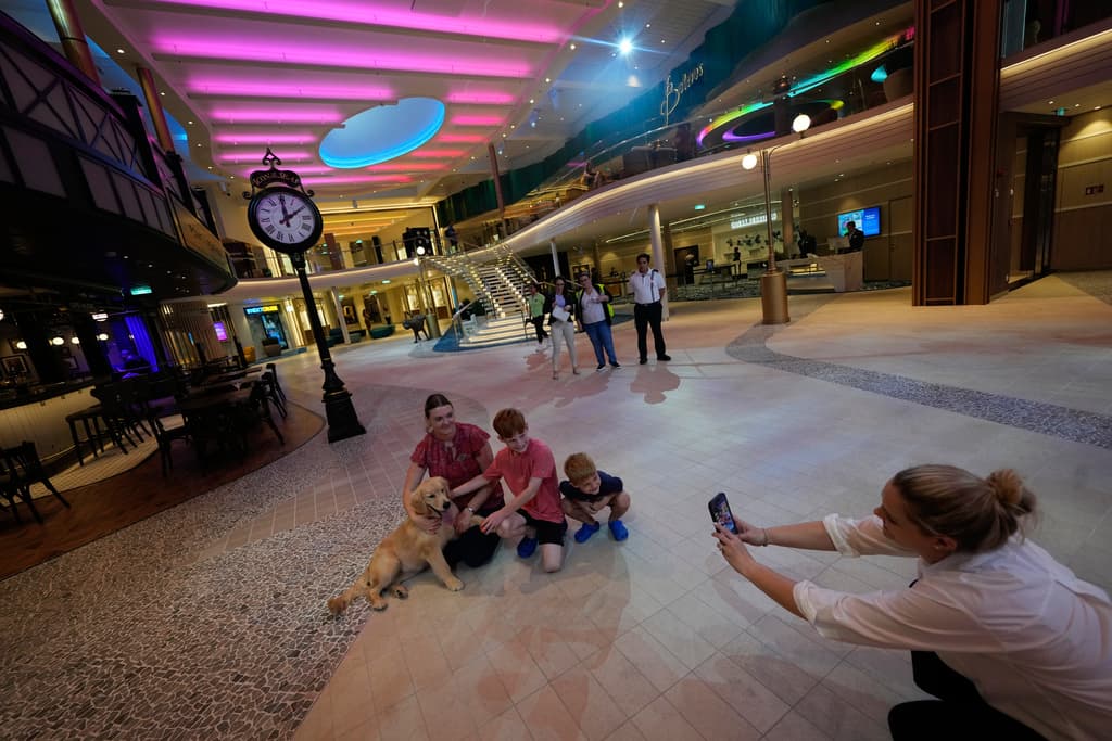 Public relations representative Jessica Milton, right, takes a picture of her sons posing with ship Chief of Staff Alison Hubble, left, and her dog Rover, dubbed the "Chief Dog Officer," during a media day preview of Icon of the Seas, the world's largest cruise ship, as it prepares for its inaugural public voyage later this month, Thursday, Jan. 11, 2024, at PortMiami in Miami. (AP Photo/Rebecca Blackwell)