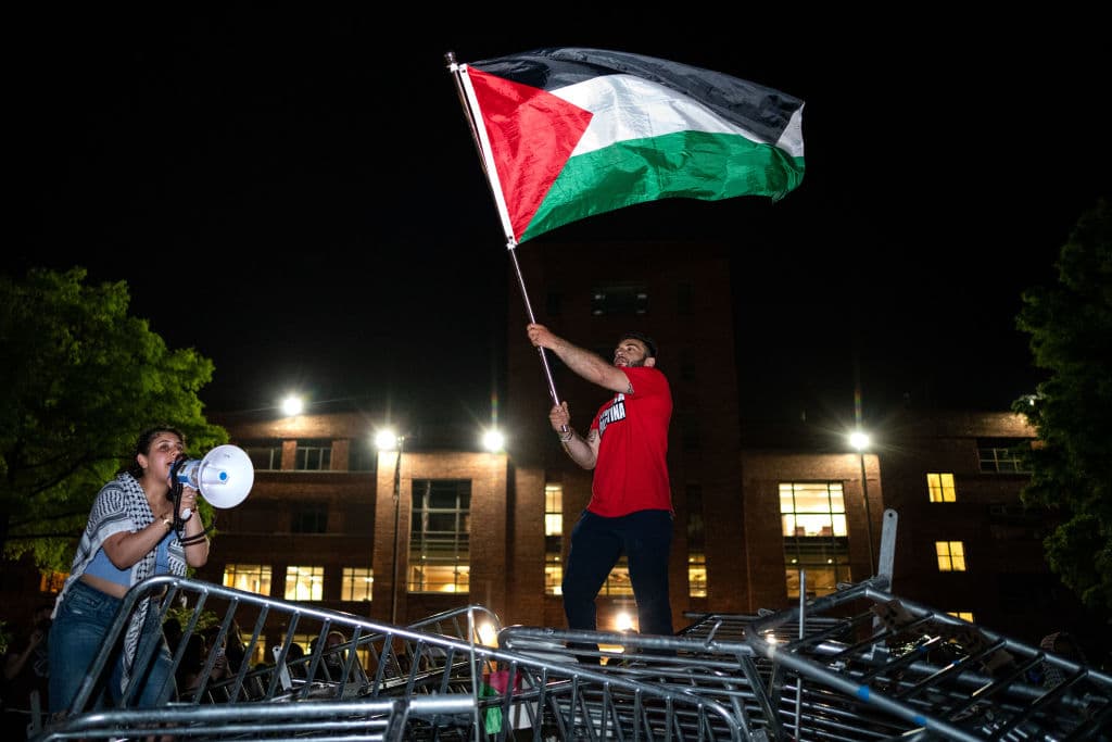 Un joven sostiene una bandera palestina mientras activistas y estudiantes cantan, en un campamento en la Universidad George Washington el 29 de abril de 2024 en Washington DC. Las protestas universitarias se extendieron por todo Estados Unidos y luego por el mundo, en
<a href="https://www.univision.com/noticias/mundo/presiones-benajamin-netanayahu-seguir-con-la-guerra-en-gaza-mantenerse-en-el-poder-supervivencia-politica">solidaridad con los palestinos. </a>Los jóvenes pedían a sus universidades que
<a href="https://www.univision.com/noticias/mundo/israel-guerra-en-gaza-transformacion-de-israel-en-un-estado-paria-analisis-luciano-zaccara">corten vínculos financieros con Israel</a> o con empresas que le financien armas para la guerra.