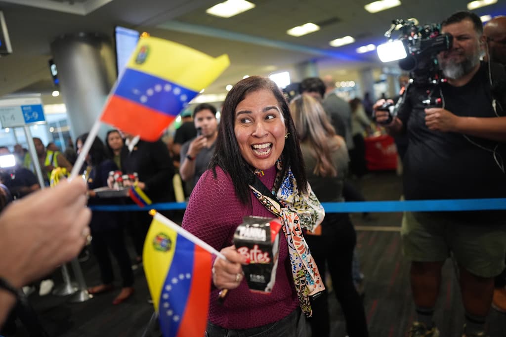Una pasajera aborda el vuelo AA3599 de American Airlines mientras sostiene una bandera venezolana.
