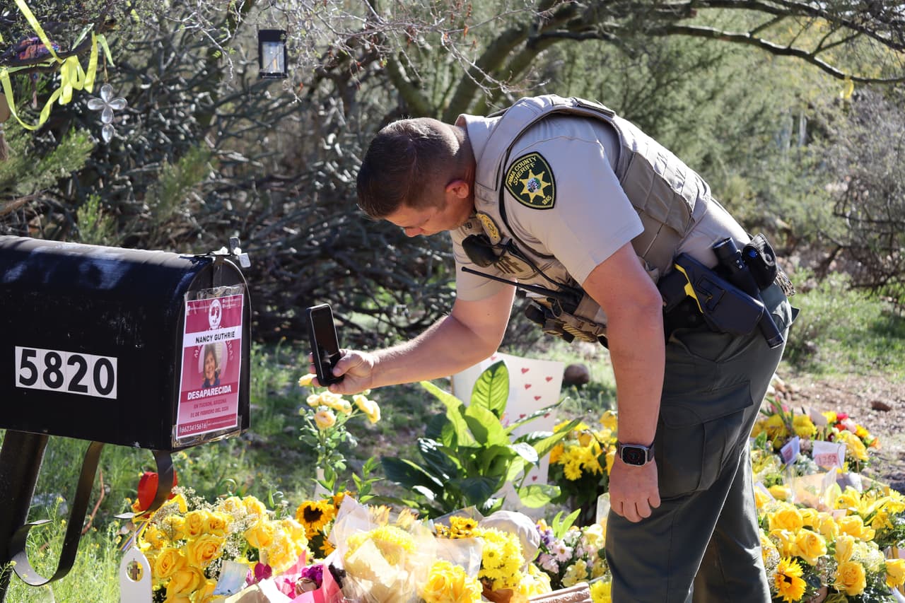 Un agente del orden público del Departamento del Sheriff del Condado de Pima fotografía un volante en un buzón en la casa de Nancy Guthrie, la madre desaparecida de la presentadora del programa "Today" Savannah Guthrie