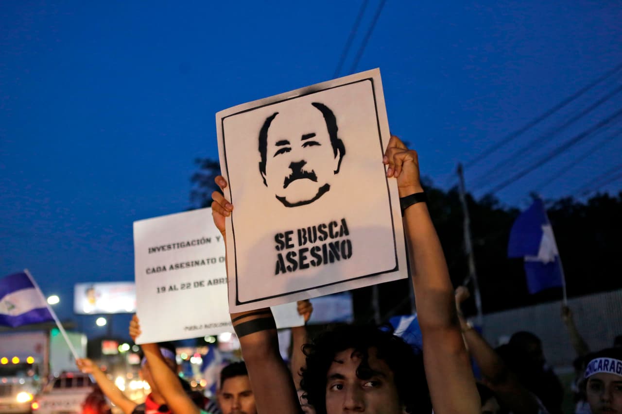 A student protester holds a sign with the face of Daniel Ortega, with the words "Wanted murderer", May 3, 2018. At least 43 people died during massive protests against a Social Security tax hike by Ortega.