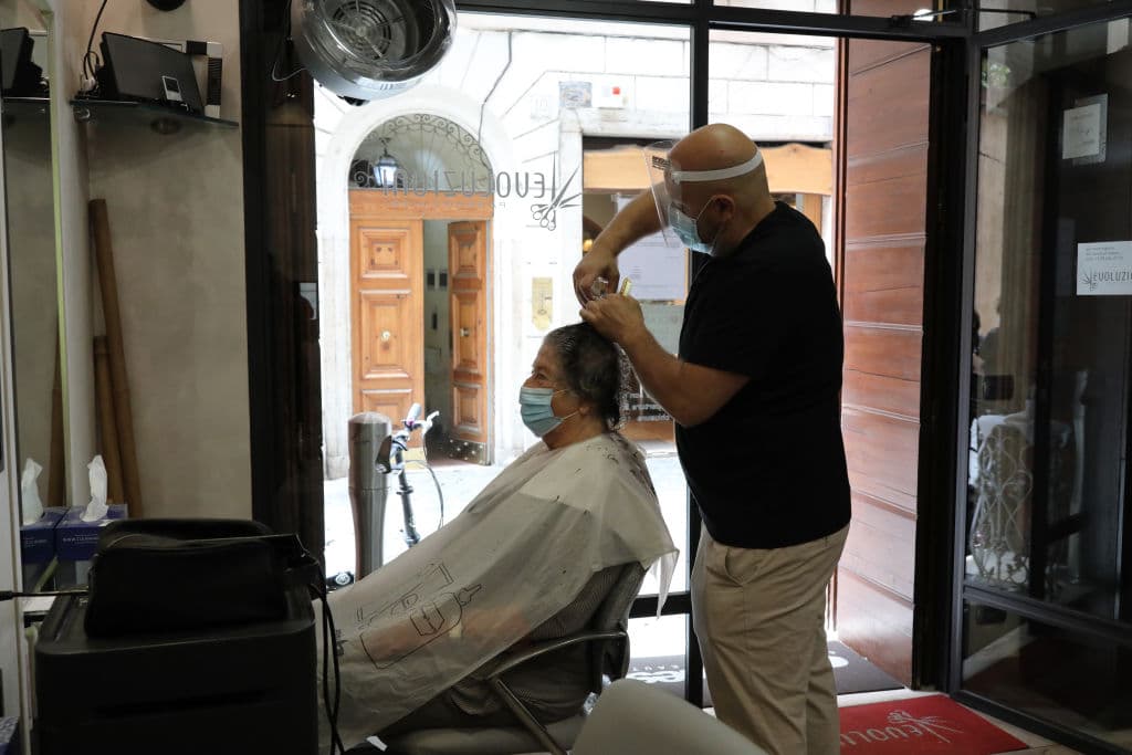 Las peluquerías también comenzaron a funcionar nuevamente luego de dos meses cerradas. En la foto, se ve a un peluquero cortando el cabello de una mujer usando la protección ordenada por las autoridades.
