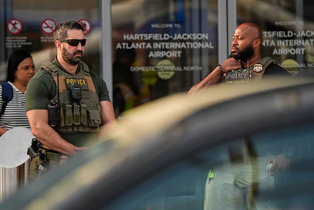 Esta foto también muestra a
<b>agentes federales parados en el exterior del aeropuerto de Atlanta. </b>
<br>
<br>Se cree que ayudarán también en la verificación inicial de identificaciones y el manejo de filas.