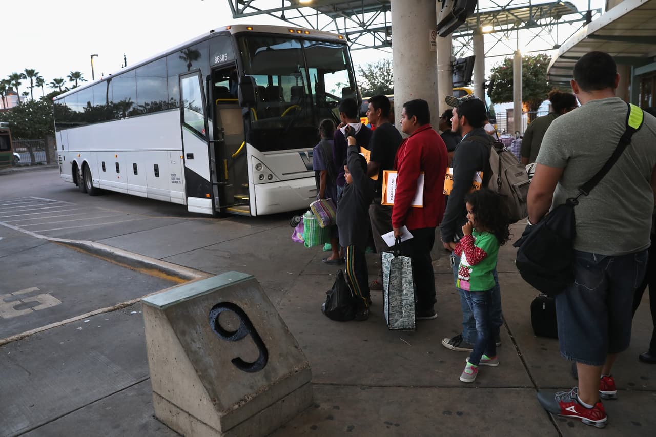 A group of immigrants from Central America line up to catch a bus after being processed by Border Patrol in McAllen, Texas. When they are released, they receive a summons to appear before a judge who will decide their future in the United States.