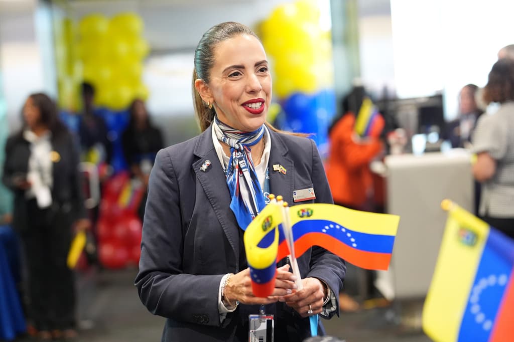 Una agente de American Airlines sostiene banderas venezolanas para repartirlas entre los pasajeros durante el embarque del vuelo AA3599.