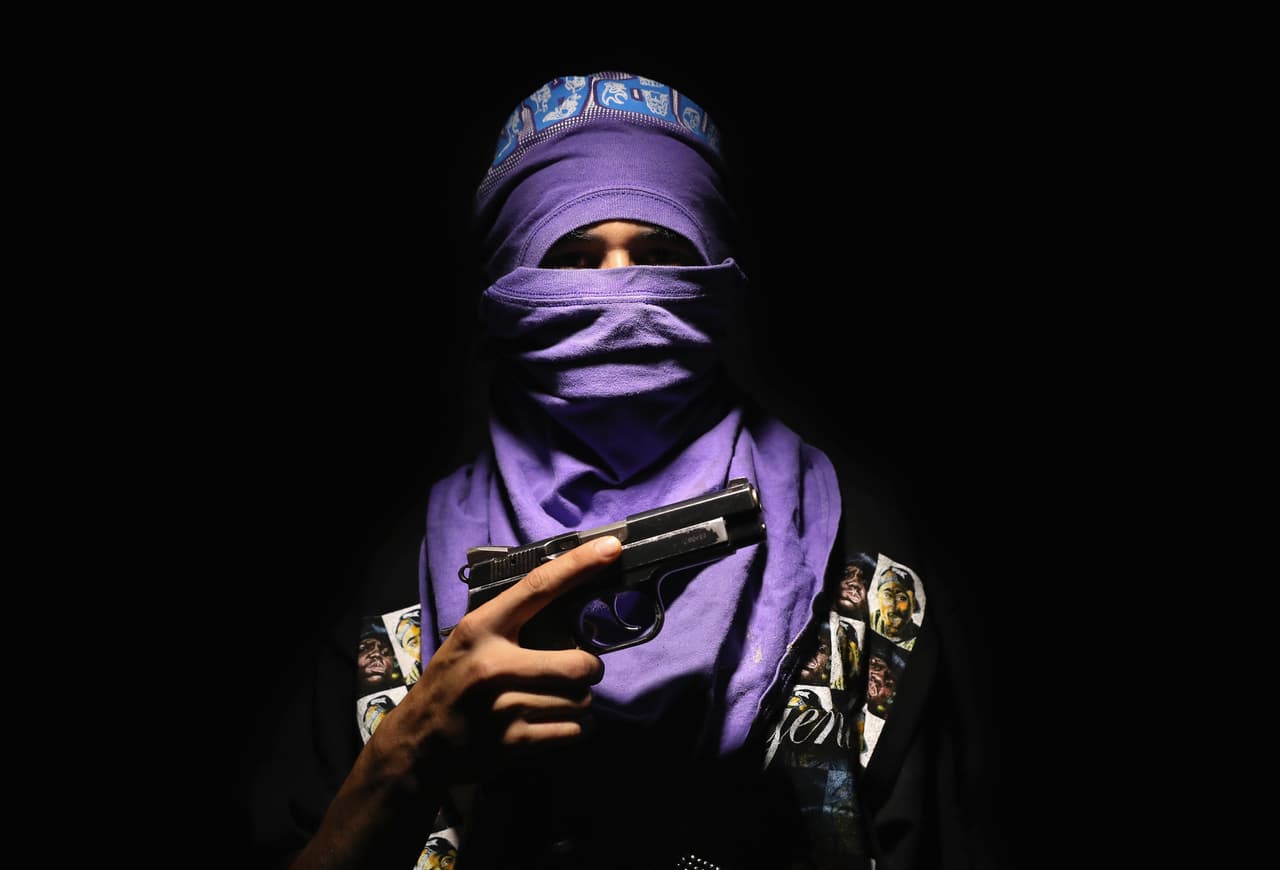 <b>Barrio 18.</b> También conocida como Calle 18, Mara 18, M-18, o la 18, se formó por inmigrantes mexicanos y jóvenes de ascendencia mexicana en Los Ángeles, en la década de 1960. Tiene una estructura similar a la de su banda rival, la MS-13, conformada por 'clicas' independientes pero interconectadas en 36 estados de EEUU, México y Centroamérica. Las autoridades vinculan a este grupo con el narcotráfico, la prostitución y el tráfico de personas, entre otros delitos. Se identifican con el número 18 y los colores negro, plateado, azul y ocasionalmente rojo. En la fotografía 'El mortal' un miembro de Barrio 18 de San Pedro Sula, Honduras.