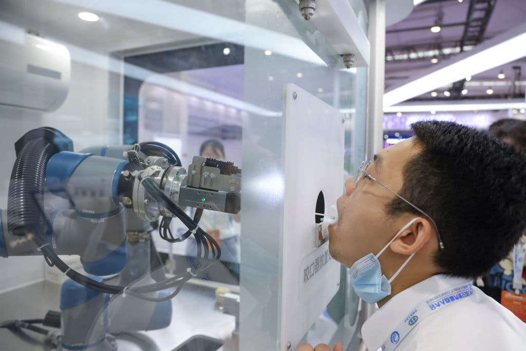<b>5.- Enfermero.</b> En la imagen, un joven participa en una demostración de un brazo robótico que recolecta muestras de hisopos para la detección de covid-19 durante la Conferencia Mundial de Robots 2022 en la Exposición Internacional Etrong de Beijing el 18 de agosto de 2022 en Beijing, China.