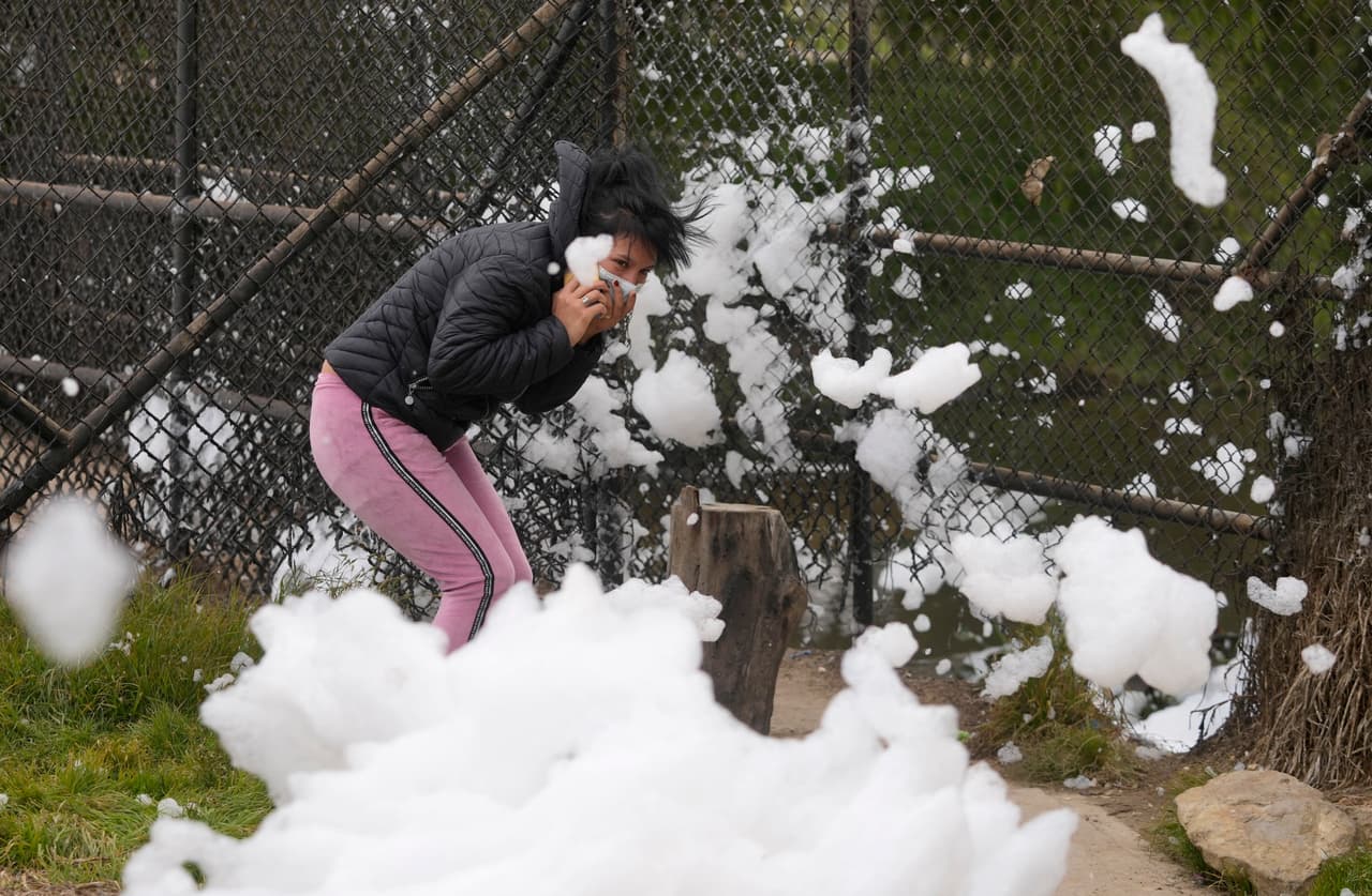 <b>Una mujer trata de eludir la espuma que vuela su vecindario. </b>Un hedor apesta en toda zona, producto de la polución del río. Desde hace varios años, los residentes se han acostumbrado
<b>a la aparición de una espuma maloliente en el río Balsillas, adonde llegan aguas residuales de la capital colombiana. </b>
<br>