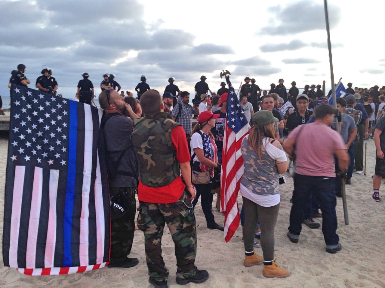 Pro-Trump supporters in military clothing and carrying a US flag with black stripes.