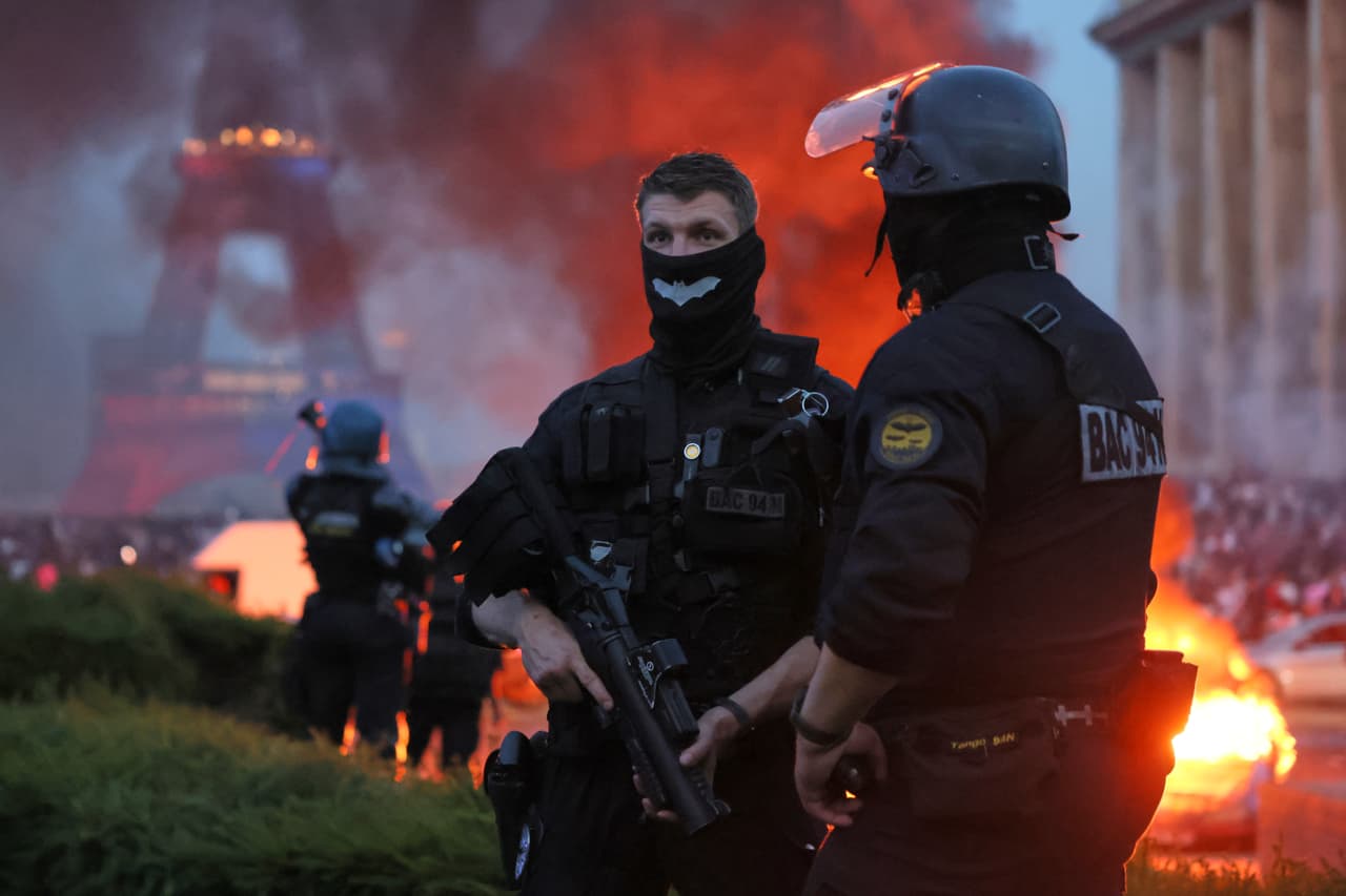 Un coche arde y estallan fuegos artificiales mientras la policía observa a los hinchas del PSG celebrar en París