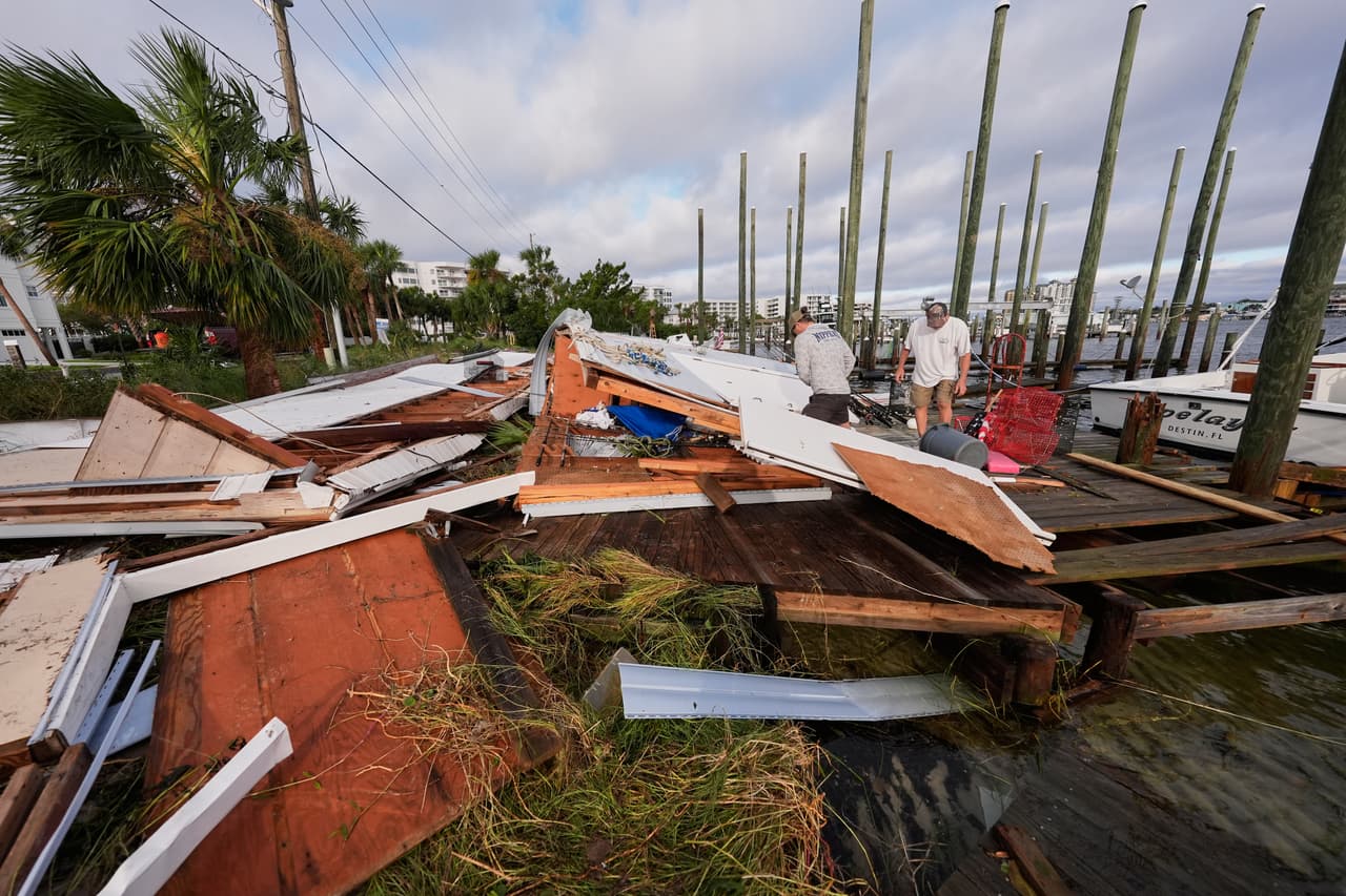 En Destin, Florida, personas sacan sus pertenencias de un cobertizo para botes que derrumbó el huracán Isaias.