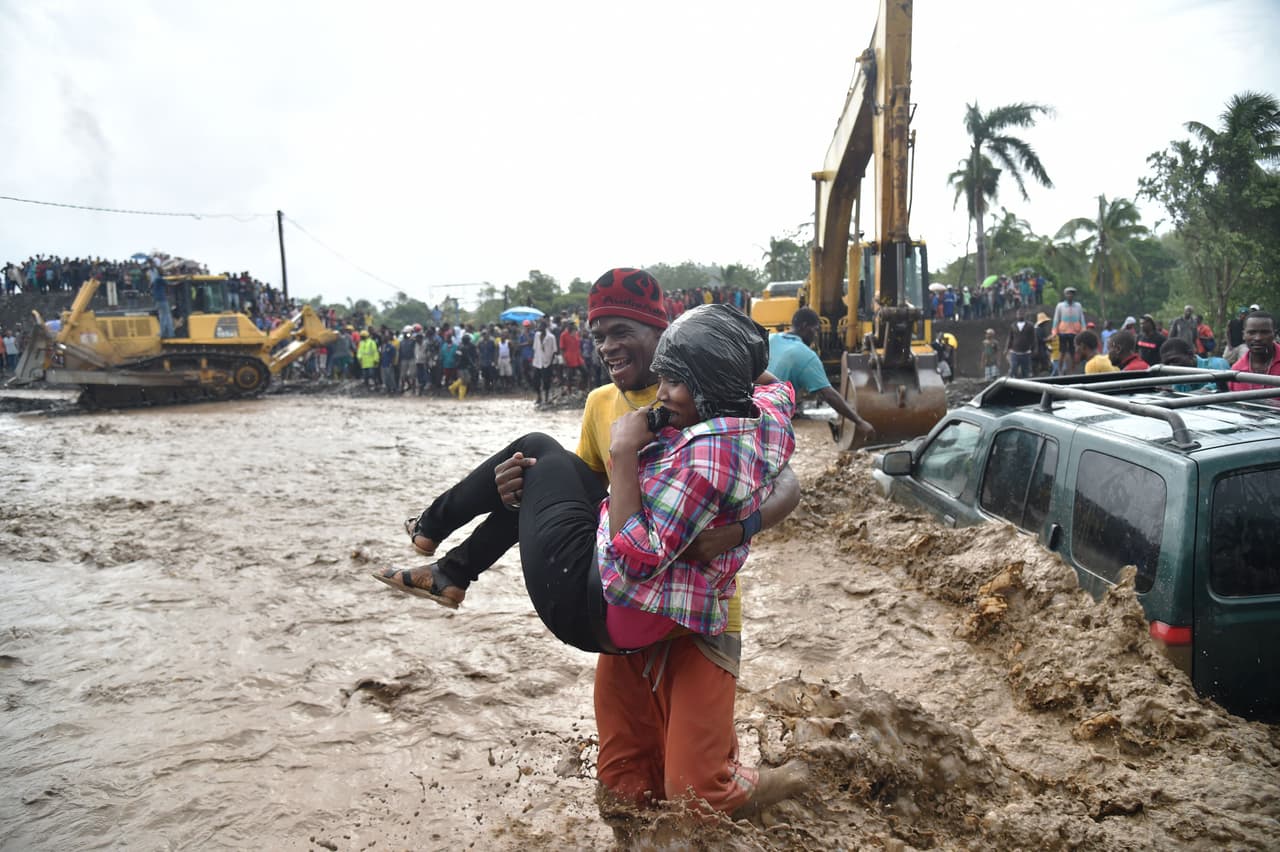 A man carries a woman in his arms across the La Digue river in Petit Goave when a bridge was swept away during Hurricane Matthew, severing road transport to the southwest peninsula.