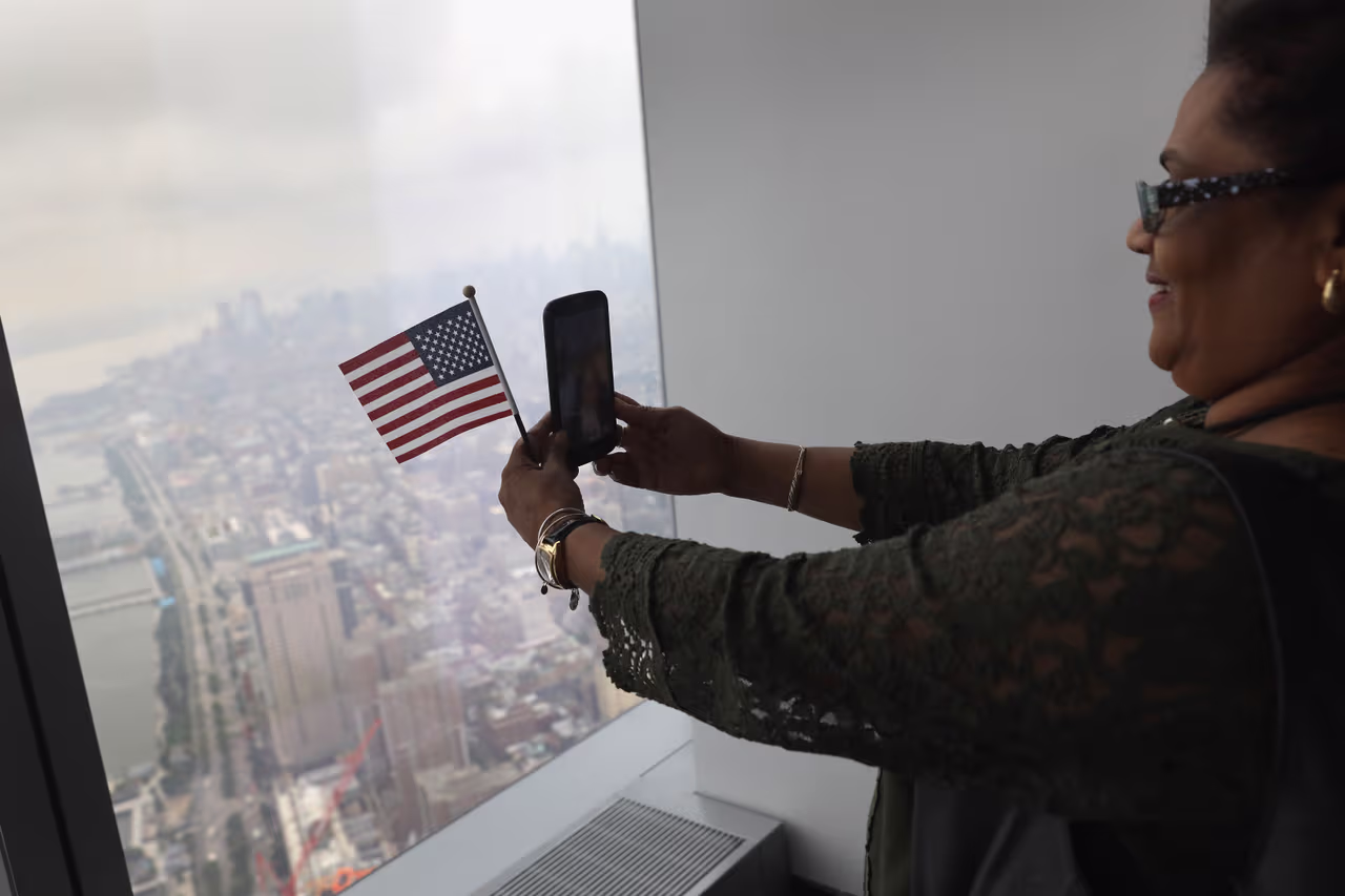 Una de las inmigrantes se toma una selfie. A lo lejos, la Estatua de la Libertad en Ellis Island. (John Moore/Getty Images)
