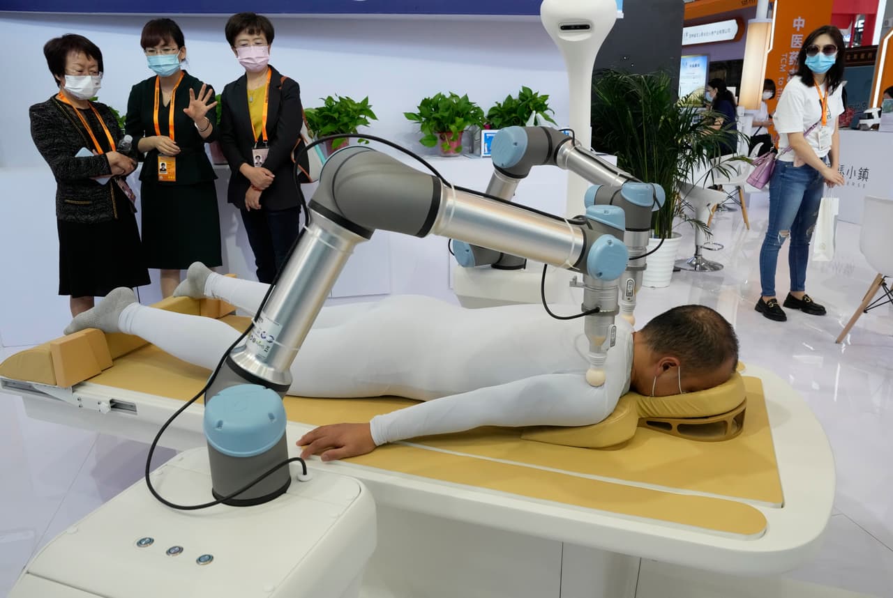 <b>6.- Masajista.</b> En la misma Conferencia Mundial de Robots 2022 en la Exposición Internacional Etrong de Beijing, un grupo de mujeres observan dos brazos robóticos llevar a cabo un tratamiento de de acupresión a un hombre.