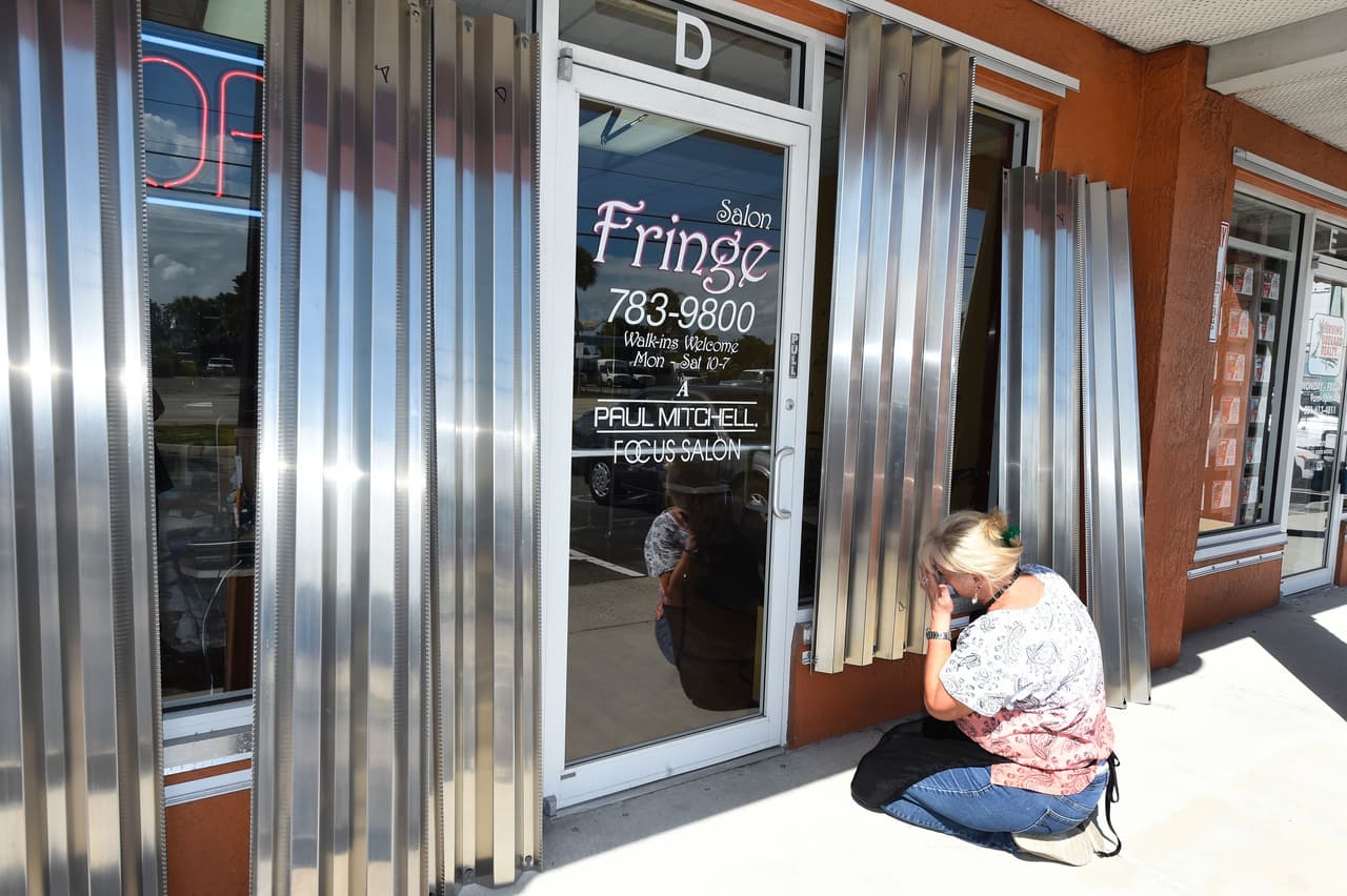 Liz Tirado tries to put up her shutters to cover the windows of her store front ahead of Hurricane Matthew on Cocoa Beach, Florida on October 5, 2016. Hurricane Matthew, the Caribbean's worst storm in nearly a decade, barreled towards the Bahamas Wednesday morning after killing nine people and pummeling Haiti and Cuba. Far to the north, the first evacuations were ordered in the United States as coastal residents prepared to escape the approaching monster storm, expected off the East Coast later this week. / AFP / RHONA WISE (Photo credit should read RHONA WISE/AFP/Getty Images)